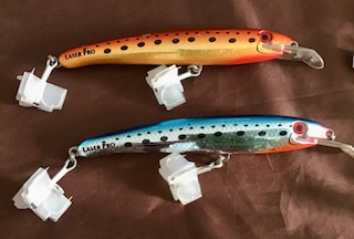 Two bibbed diving lures, one is orange, the other metallic silver and blue. The lures are trolled for tuna fishing.